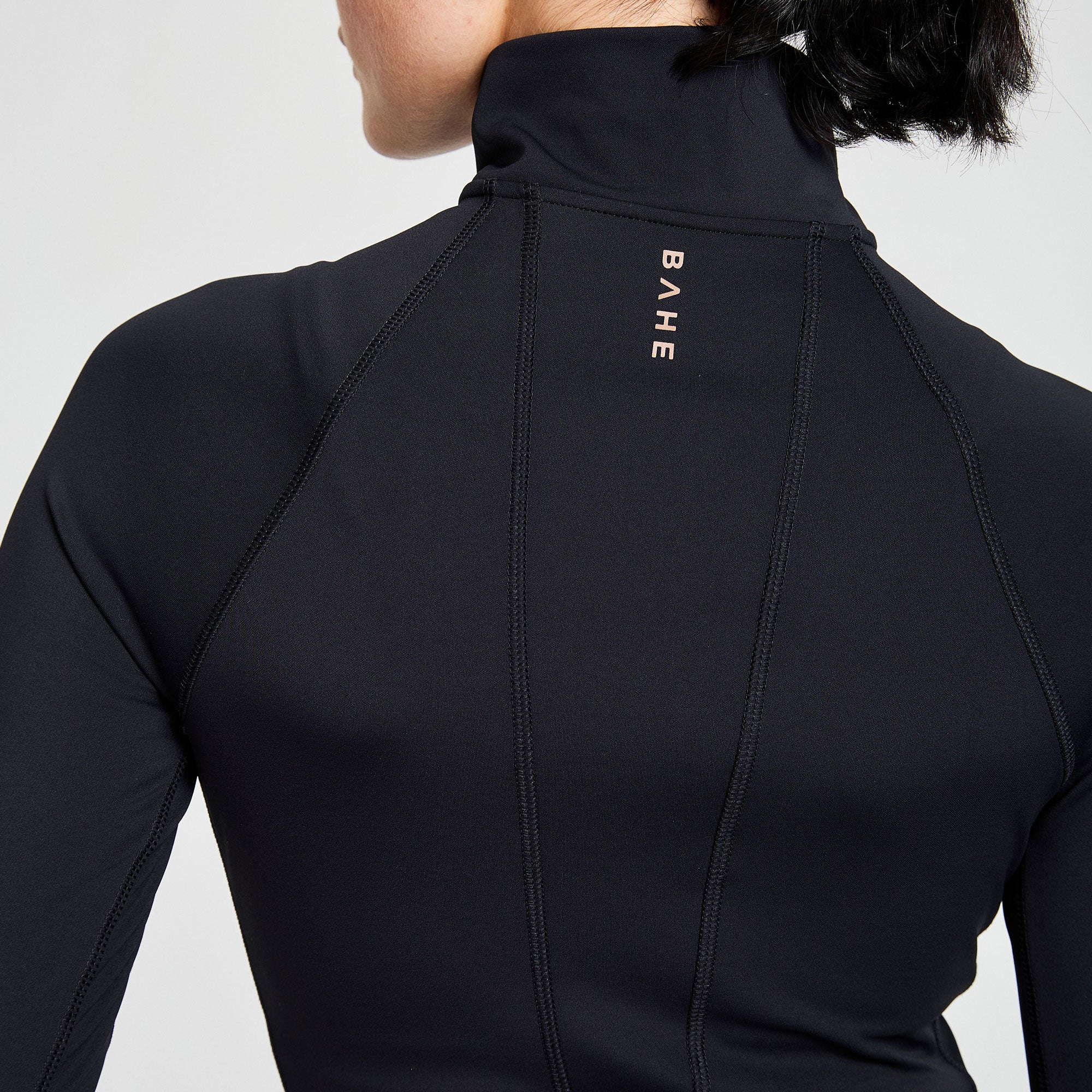 Back of black attune zipped jacket with BAHE logo details