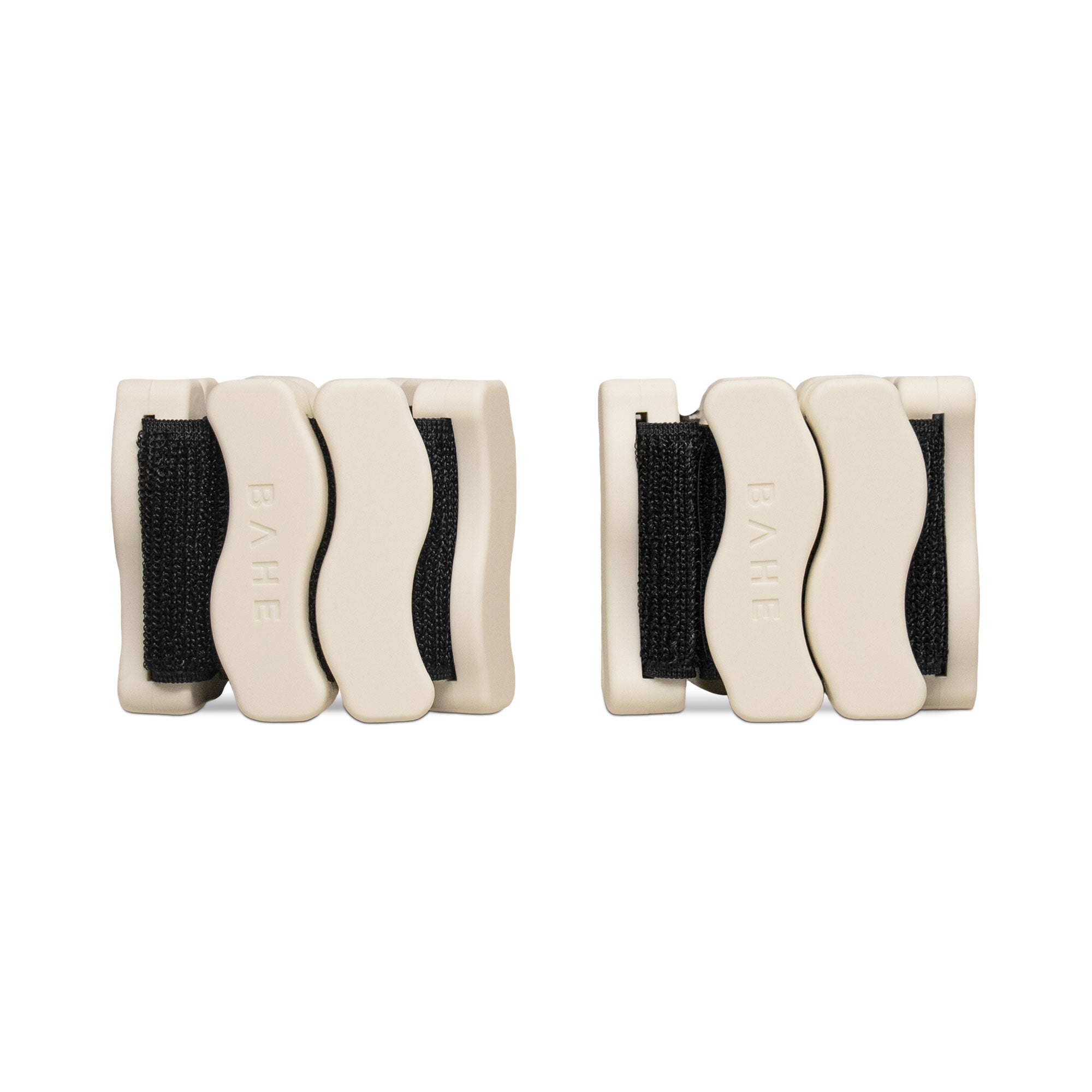 A pair of beige-colored silicone wrist/ankle weights, with black straps and a wave-like design, on a white background.